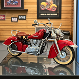 Red Indian motorcycle model on a reflective surface with a wooden wall background