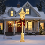 Decorative outdoor light fixture with a red bow in front of a house during Christmas.