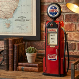 Vintage-style red Ampol gas pump on a wooden surface with books and a map in the background.