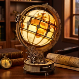 Decorative globe with mechanical design on a wooden surface, surrounded by books and maps.
