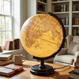 World globe on a wooden table with books and a mug in a cozy room.