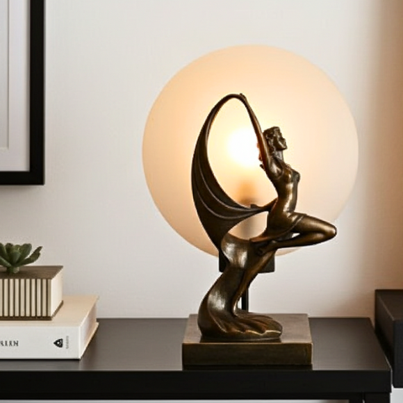 Decorative table lamp with a bronze sculpture of a person on a white wall background