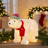 Decorative polar bear figure with a red scarf and hat in a festive setting.