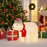 Decorative light-up polar bear with a red scarf in front of a Christmas tree and presents.