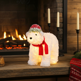 Decorative white dog figure with a red scarf and hat in front of a fireplace.