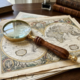 Vintage magnifying glass on an old world map with books in the background
