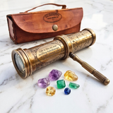 Vintage-style brass kaleidoscope with leather  case and colorful gemstones on a marble surface