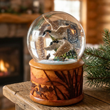 Decorative snow globe with ducks on a wooden look ceramic stand in front of a fireplace.