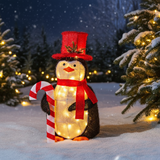 Decorative penguin with lights, candy cane, and top hat in a snowy outdoor setting.