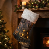 Decorative Christmas stocking hanging by a fireplace with a lit candle and Christmas tree.