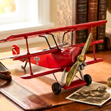 Red model airplane on a wooden surface with books and an old photo in the background