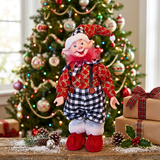 Elf doll in front of a decorated Christmas tree with presents.