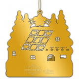 Gold Christmas ornament shaped like a house with tree silhouettes on a white background