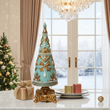 Decorative Christmas tree with gold and blue accents on a table in a room with a window view of snow.