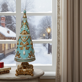 Decorative Christmas bell with gold accents on a table in front of a snowy window.