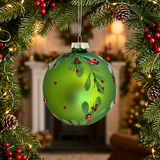 Green Christmas ornament with mistletoe design hanging among festive decorations.