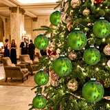 Decorated Christmas tree with green ornaments in a formal room setting.