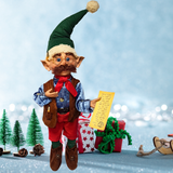 Elf doll holding a letter with Christmas trees and presents in the background