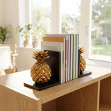 Pineapple-shaped bookends on a desk with books in a home office setting.