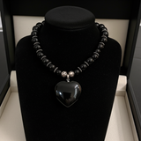 Black Agate beaded necklace with a heart pendant on a black stand.