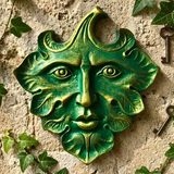 Greenman face sculpture on a textured wall with ivy