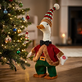 Decorative goose figurine in festive attire next to a Christmas tree with ornaments.