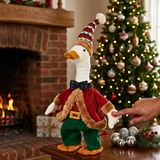 Decorative goose figurine in festive attire with a Christmas tree and fireplace in the background