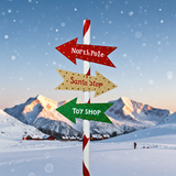 Decorative signpost with 'North Pole', 'Santa Stop', and 'Toy Shop' directions against a snowy mountain backdrop.