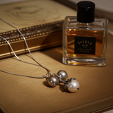 Pearl necklace and perfume bottle on a textured surface