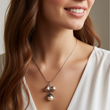 Woman wearing a necklace with three pendants against a neutral background