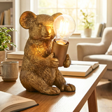 Gold bear statue holding a light bulb on a table in a cozy living room.