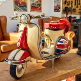 Model scooter with British flag design on a wooden surface, with a living room background.