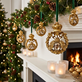 Decorative Christmas ornaments hanging on a mantelpiece with a fireplace and tree in the background.