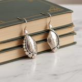 Silver earrings on a stack of books with a marble surface