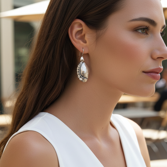 Close-up of a woman wearing silver earrings with a blurred background