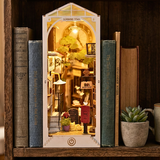 Miniature model of a town framed by books on a wooden shelf.