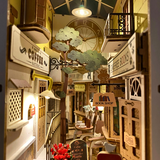 Miniature model of a cozy street with shops and a clock, resembling a bookshop.