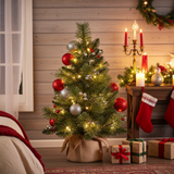 Decorated Christmas tree with ornaments and lights in a festive room setting.