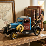 Model of a vintage tow truck on a wooden surface with books and a map in the background