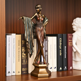 Bronze statue of a woman with a scarf among books on a wooden shelf