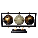 A set of three world globes, with two in black and gold colors and one in cream and gold, displayed on a black metal stand with a wooden base.
