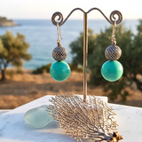 Turquoise earrings on a stand with a scenic background
