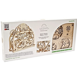 UGears Model + Theater + Magnets + Theory wooden mechanical model kit in its original white packaging box, showing the assembled wooden gears and clockwork model through a clear window.