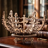 A wooden 3D laser-cut puzzle model of a ballerina surrounded by coral or shell-like forms, displayed on a dark wooden table with vintage books in a softly blurred library background.