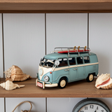 Model van with surfboard on a shelf with seashells and a clock.