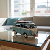 Model of a vintage van with a surfboard on a glass table in a living room.