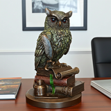 Statue of an owl on books with a desk and chair in the background