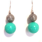A pair of turquoise and sterling silver earrings with a geometric pattern resembling a disco ball.